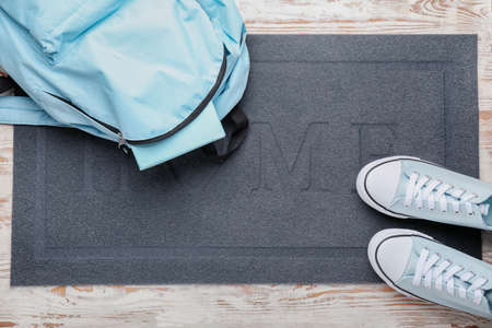 Door mat, shoes and backpack on floorの写真素材