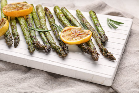 Cooked asparagus with lemon on boardの写真素材