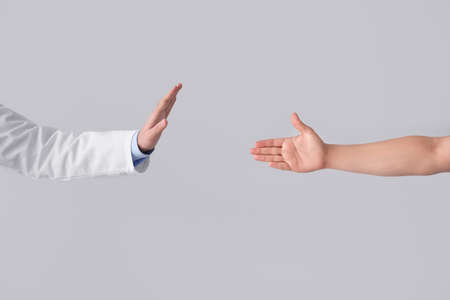 Doctor refusing to shake hand of patient on light background. Concept of social distanceの写真素材
