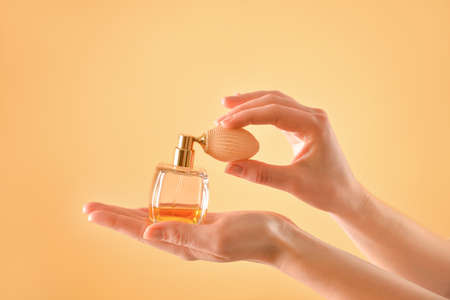 Female hands with perfume on color backgroundの写真素材