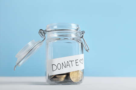 Glass jar with coins on table. Concept of donationsの写真素材