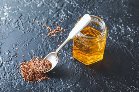 Jar with flax oil and seeds on dark tableの写真素材