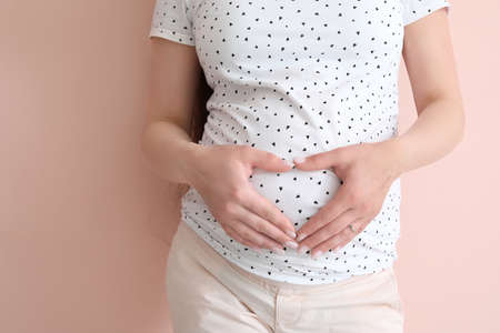 Beautiful pregnant woman on color backgroundの写真素材