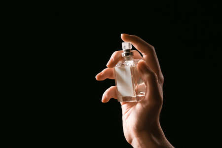Female hand with perfume on dark backgroundの写真素材