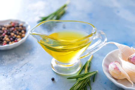 Gravy boat of rosemary oil and spices on color backgroundの写真素材