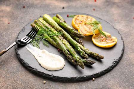 Cooked asparagus with sauce and lemon on gray backgroundの写真素材