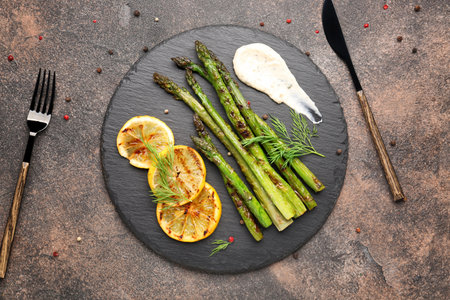 Cooked asparagus with sauce and lemon on gray backgroundの写真素材