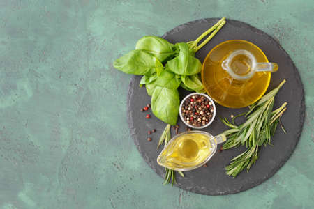 Gravy boat and bottle of rosemary oil on color backgroundの写真素材