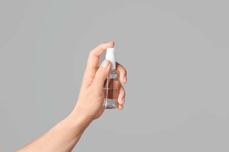 Female hand with sanitizer on gray background
