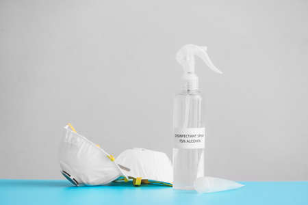 Bottle of disinfectant and medical masks on table