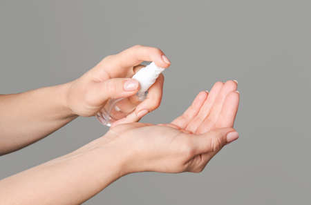 Woman using sanitizer on gray backgroundの写真素材