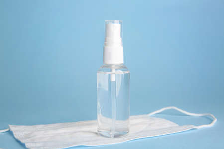 Bottle of disinfectant and medical mask on color backgroundの写真素材