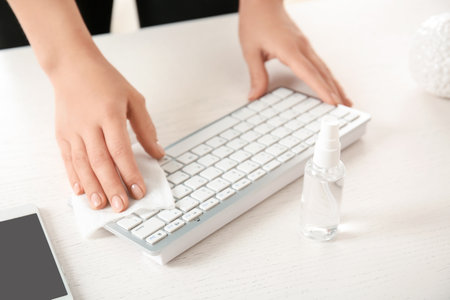 Woman disinfecting her workplace in officeの写真素材