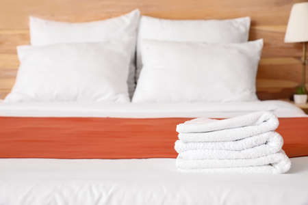 Clean towels on bed in hotel roomの写真素材