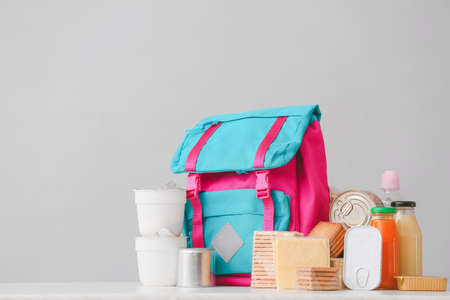 Schoolbag with different products on light background. Concept of Backpack Food Programの写真素材
