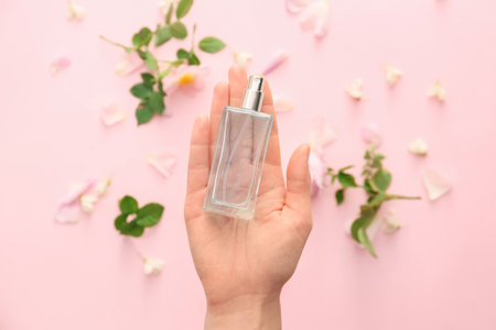 Female hand with floral perfume on color background