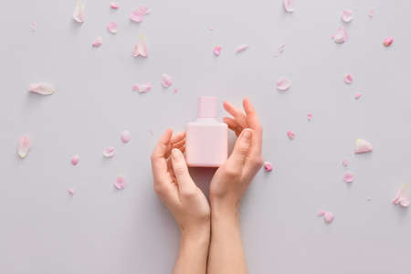 Female hands with floral perfume on light backgroundの写真素材