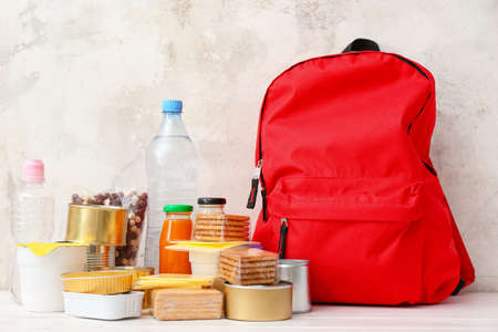 Schoolbag with different products on table. Concept of Backpack Food Programの写真素材