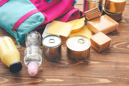 Schoolbag with different products on wooden background. Concept of Backpack Food Programの写真素材