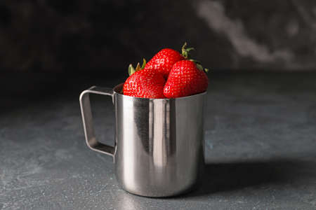 Mug with ripe strawberry on dark backgroundの写真素材