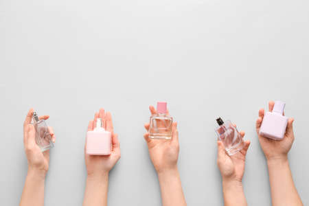 Female hands with perfumes on light backgroundの写真素材