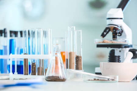 Samples of soil, microscope and glassware on table in laboratoryの写真素材