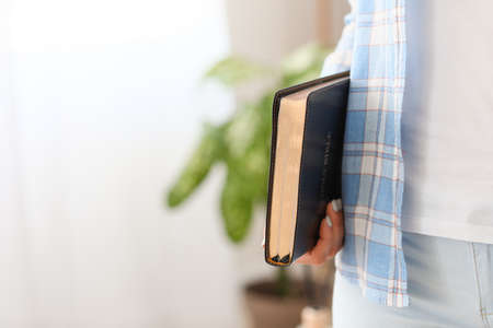 Young woman with Bible at home, closeup