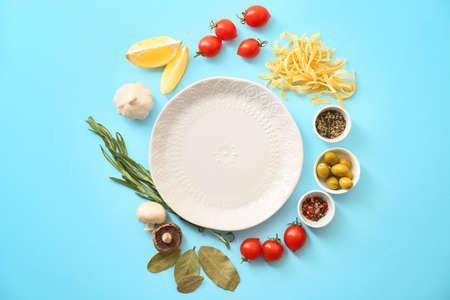 Plate with uncooked pasta and products on color backgroundの写真素材