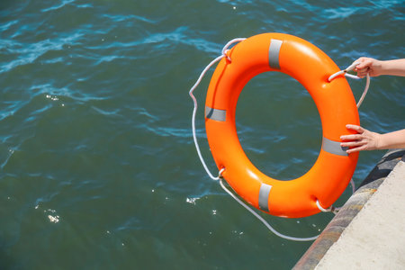 Woman throwing lifebuoy ring on waterの写真素材