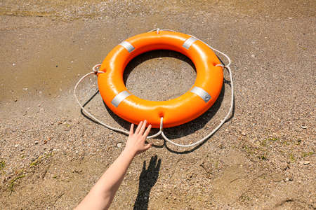 Woman making long arm for lifebuoy ring on beach