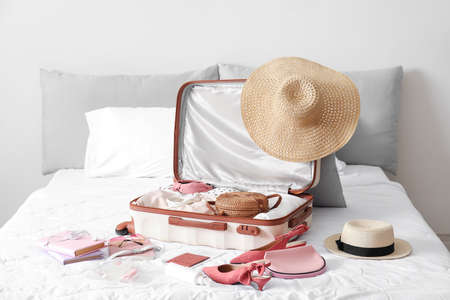 Suitcase with female clothes and accessories on bedの写真素材