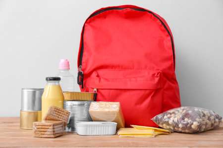 Schoolbag with different products on table. Concept of Backpack Food Programの写真素材