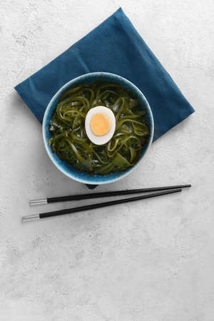 Bowl with tasty seaweed and chopsticks on light backgroundの写真素材
