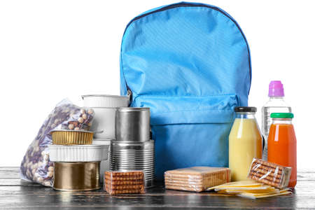 Schoolbag with different products on table against white background. Concept of Backpack Food Programの写真素材