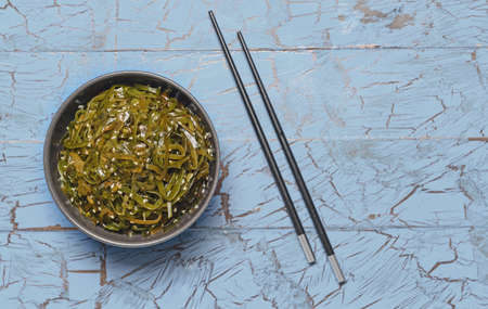 Bowl with tasty seaweed and chopsticks on tableの写真素材