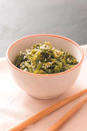 Bowl with tasty seaweed and chopsticks on tableの写真素材