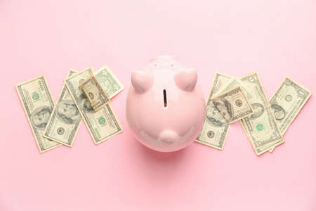 Piggy bank and money on color background