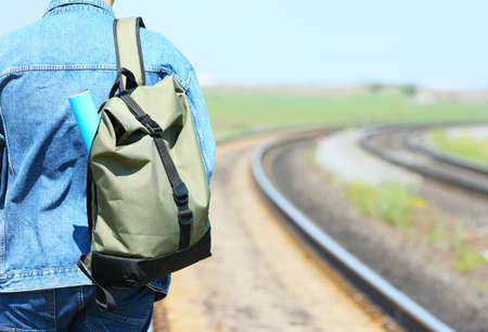 Female traveler with backpack walking along railway tracksの写真素材