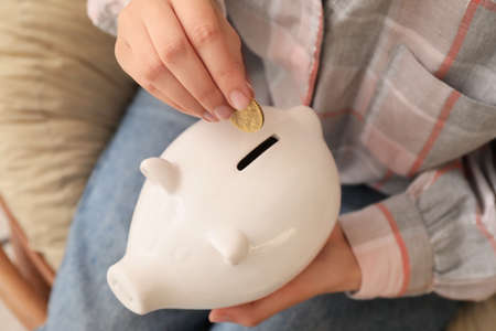 Woman putting money in piggy bank closeupの写真素材
