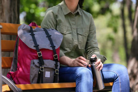 Female traveler with backpack sitting on bench in parkの写真素材