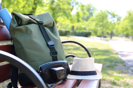Traveler's backpack and hat on bench in green parkの写真素材