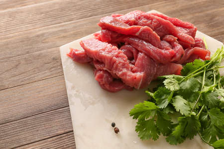 Pieces of fresh beef meat with herbs on table