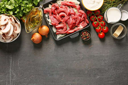 Ingredients for beef stroganoff with mushrooms on dark background
