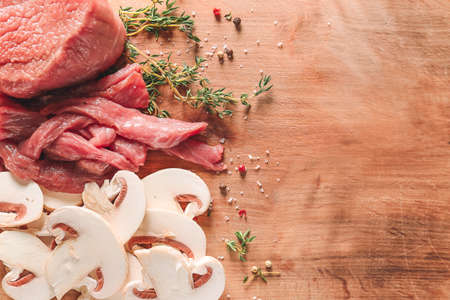 Pieces of fresh beef meat with mushrooms and spices on tableの写真素材