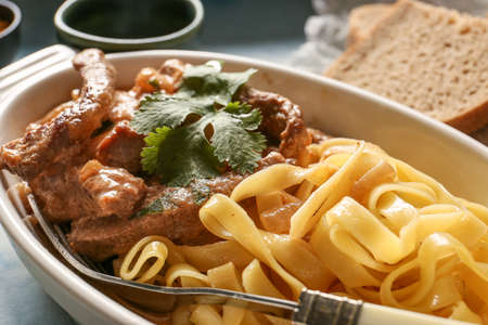 Tasty beef stroganoff with pasta on table, closeup