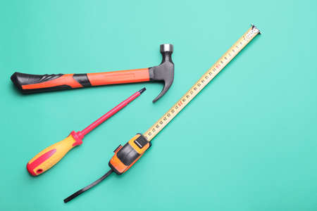 Measuring tape with builder's supplies on color background