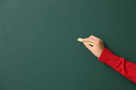Cute little schoolgirl writing on blackboard in classroomの写真素材