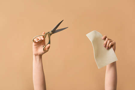 Female hands tailor's scissors and fabric on color backgroundの写真素材