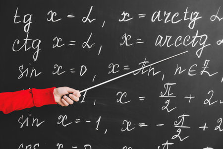 Cute little schoolgirl pointing at blackboard in classroom