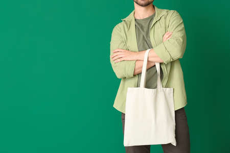 Young man with eco bag on color background